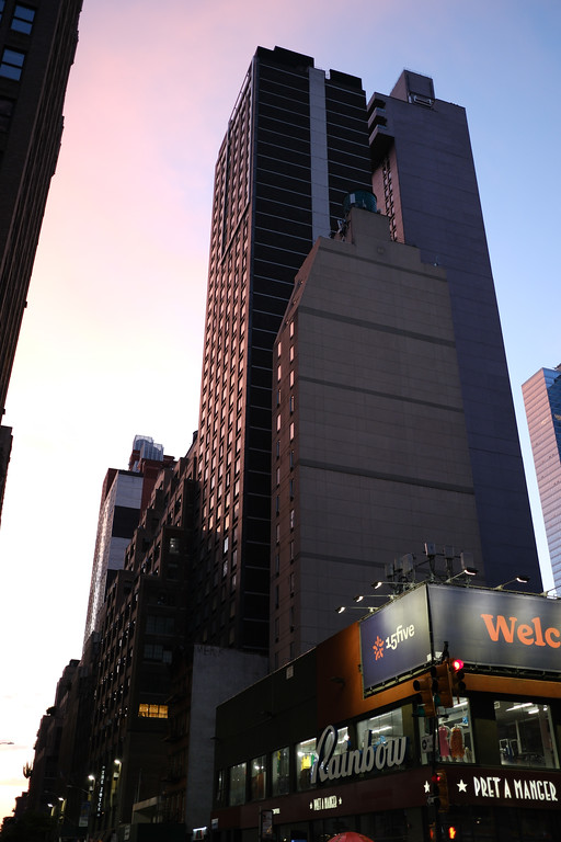 A tall city building against a pink evening sky