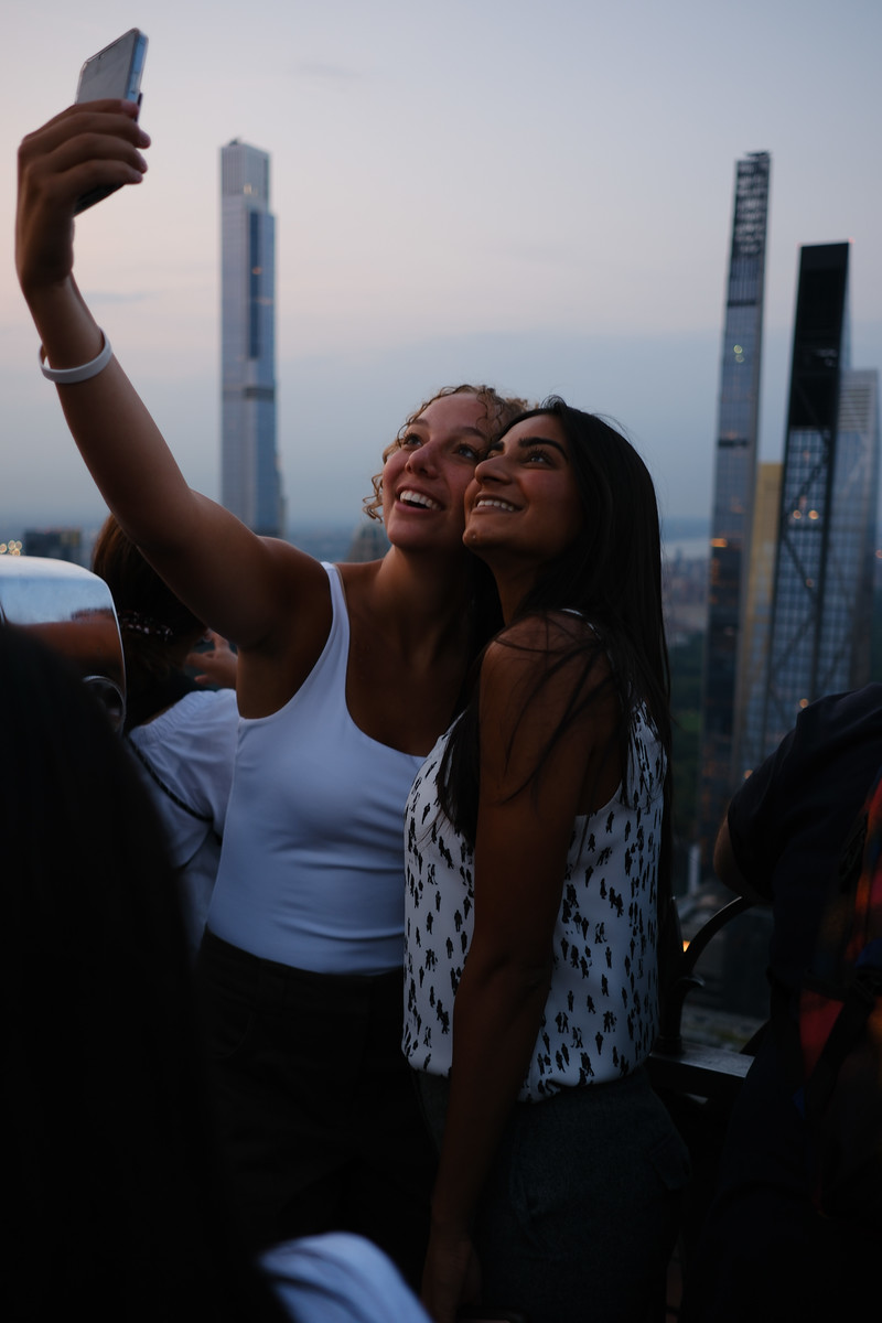 Two friends taking a selfie above the city at dusk