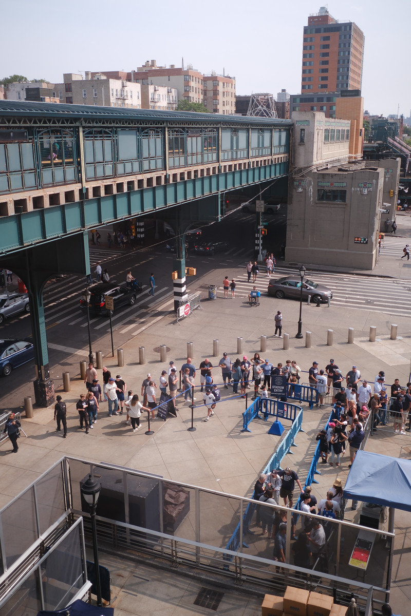 People gathering in a plaza beside an elevated walkway