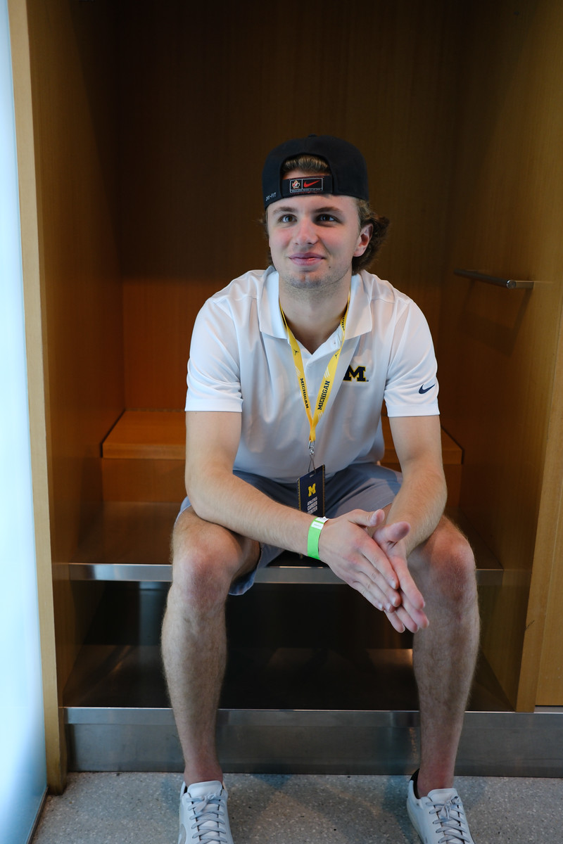 A person in a white shirt seated in a warm wood-lined alcove